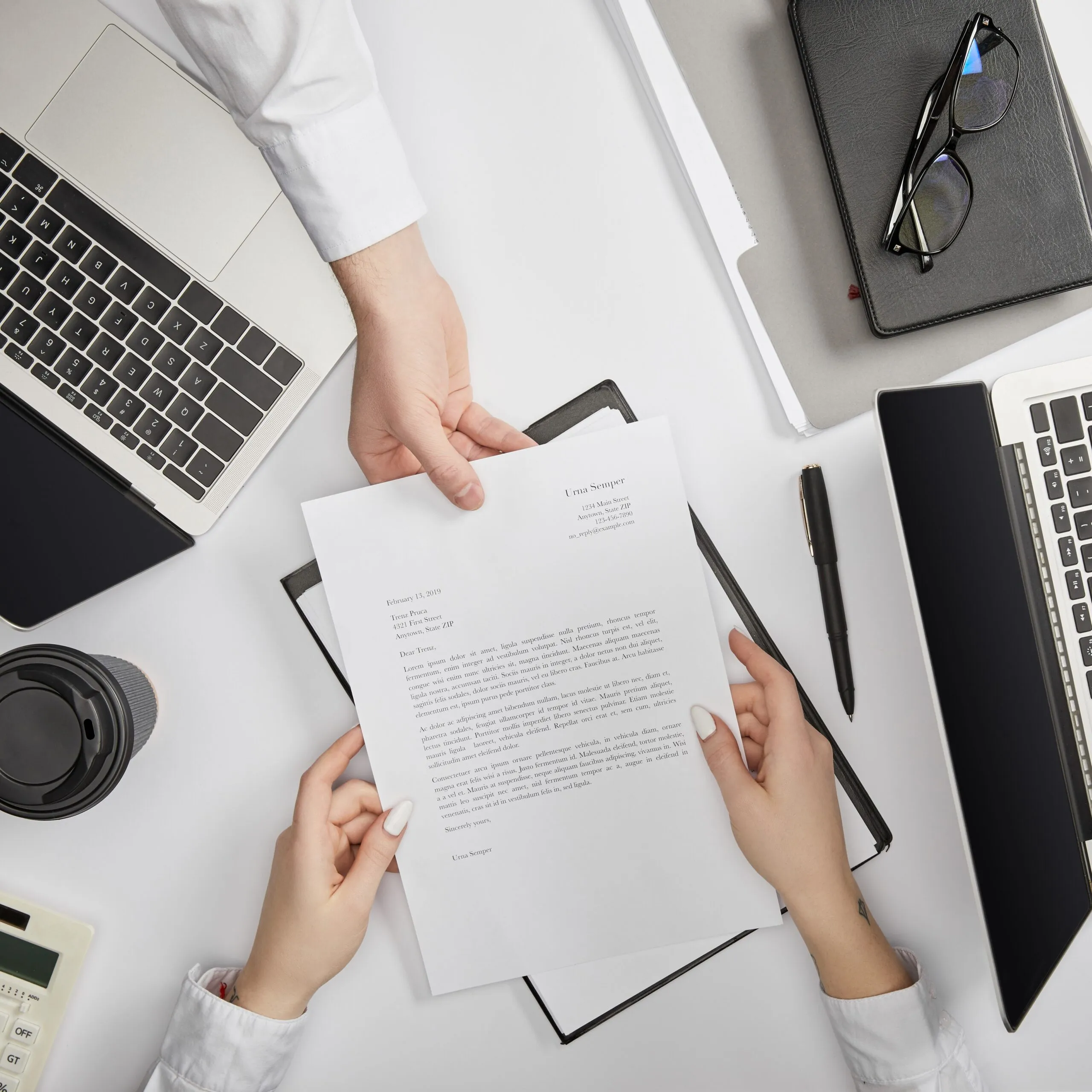top view of businesspeople typing on laptop and holding document